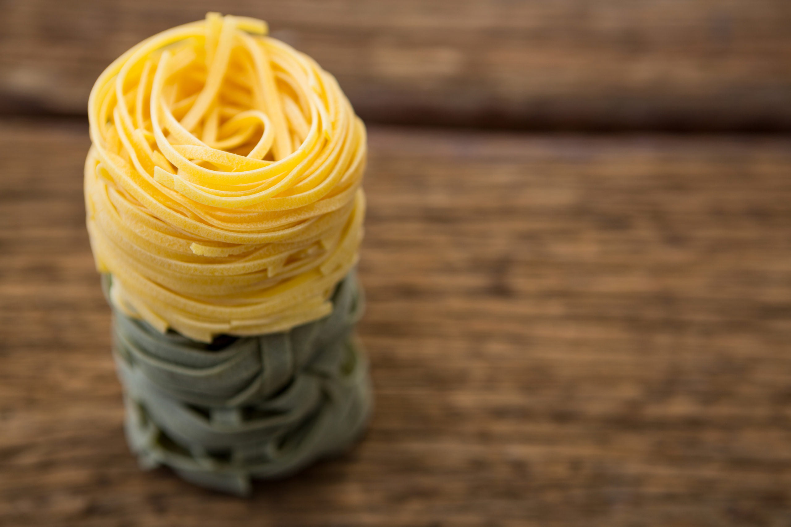 Stack of tagliatelle pasta on wooden surface