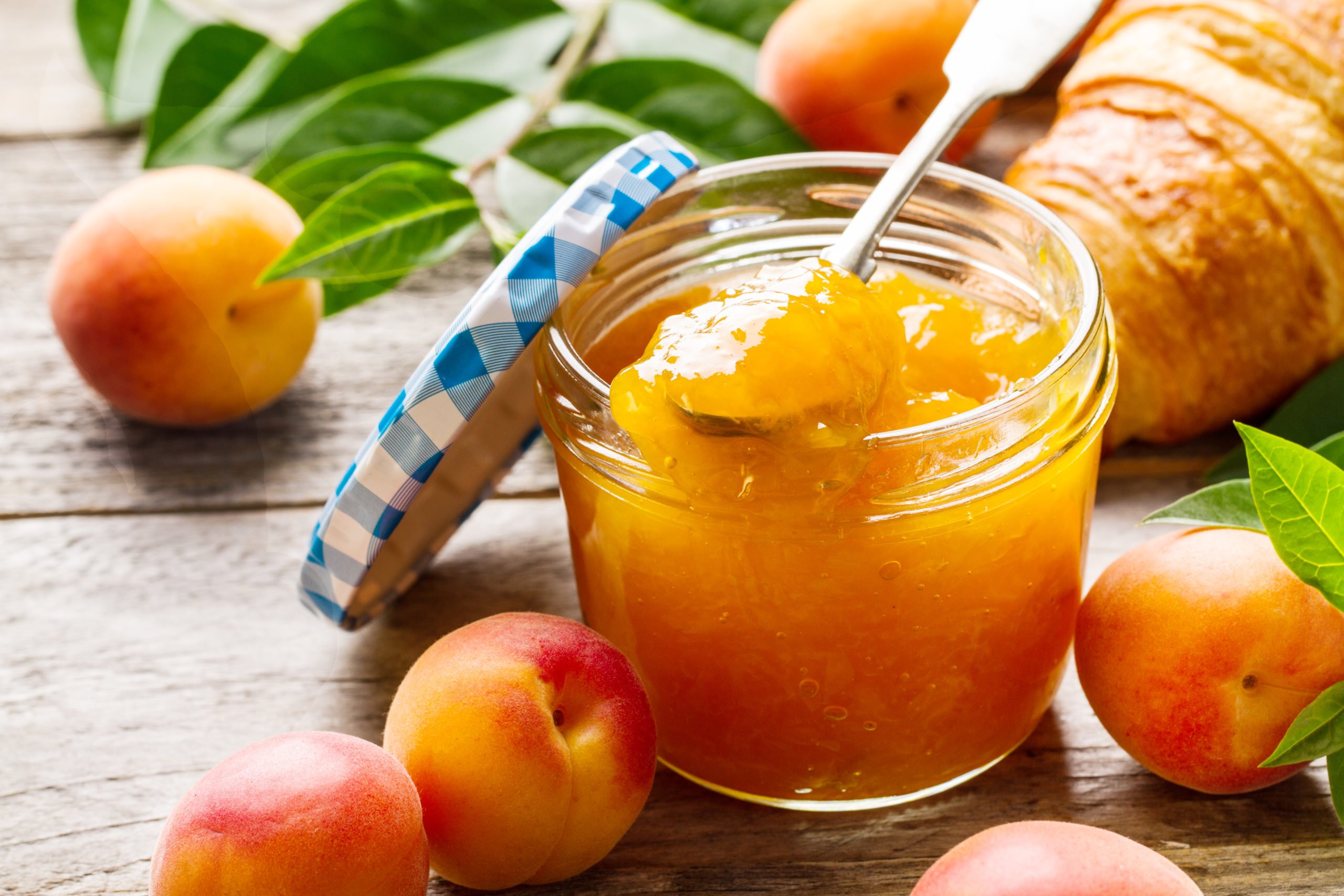 Tasty fruit orange apricot jam in glass jar with fruits on wooden table. Closeup.
